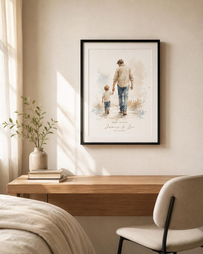 Puede incluir: Impresi&oacute;n art&iacute;stica enmarcada con una ilustraci&oacute;n en acuarela de un padre y un ni&ntilde;o caminando juntos. La impresi&oacute;n incluye el texto "Daddy and Me" y los nombres "James & Leo" con una fecha. La obra de arte est&aacute; enmarcada en un marco negro.