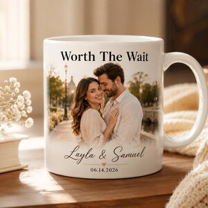 Op de afbeelding: Witte keramische mok met een foto van een stel, met de tekst "Worth The Wait", en de namen "Layla & Samuel" met de datum "06.14.2026". De mok heeft een gebogen handvat en een glanzende afwerking.
