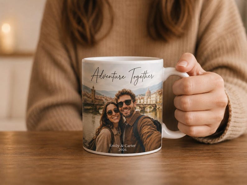 Pu&ograve; includere: Tazza in ceramica bianca con la scritta "Adventure Together" e una foto di una coppia. La foto mostra una coppia davanti a un ponte e degli edifici. La tazza riporta anche i nomi "Emily & Carter" e l'anno "2026".