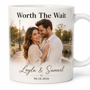 Op de afbeelding: Witte keramische mok met een foto van een stel. De mok heeft de tekst "Worth The Wait" bovenaan, met de namen "Layla & Samuel" en de datum "06.14.2026" onderaan. De handgreep is wit.