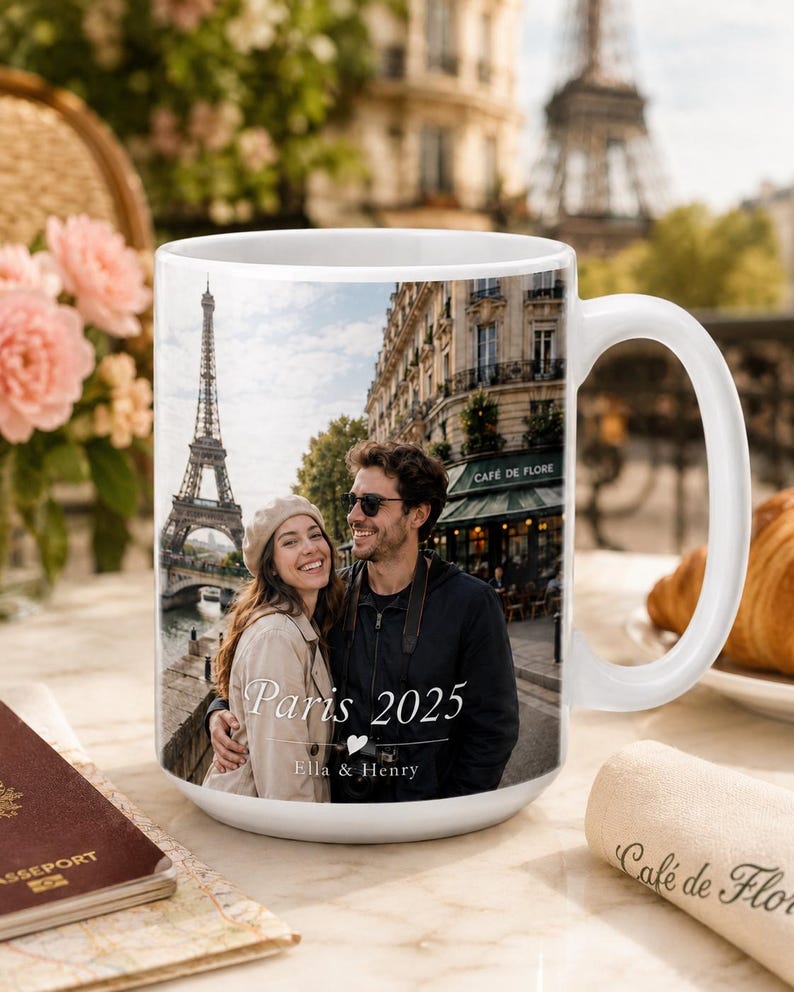 Peut inclure: Mug en c&eacute;ramique blanche avec une photo d'un couple &agrave; Paris, avec la Tour Eiffel en arri&egrave;re-plan. Le mug porte l'inscription "Paris 2025" et les noms "Ella & Henry". Une anse blanche est visible sur le c&ocirc;t&eacute; droit.