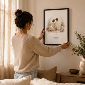 K&ouml;nnte beinhalten: Ein gerahmter Aquarelldruck mit einem Paar, mit dem Text "You and Me" sowie Namen und Datum. Das schwarz gerahmte Kunstwerk wird an einer Wand aufgeh&auml;ngt. Das Bild hat eine neutrale Farbpalette und befindet sich in einer h&auml;uslichen Umgebung.