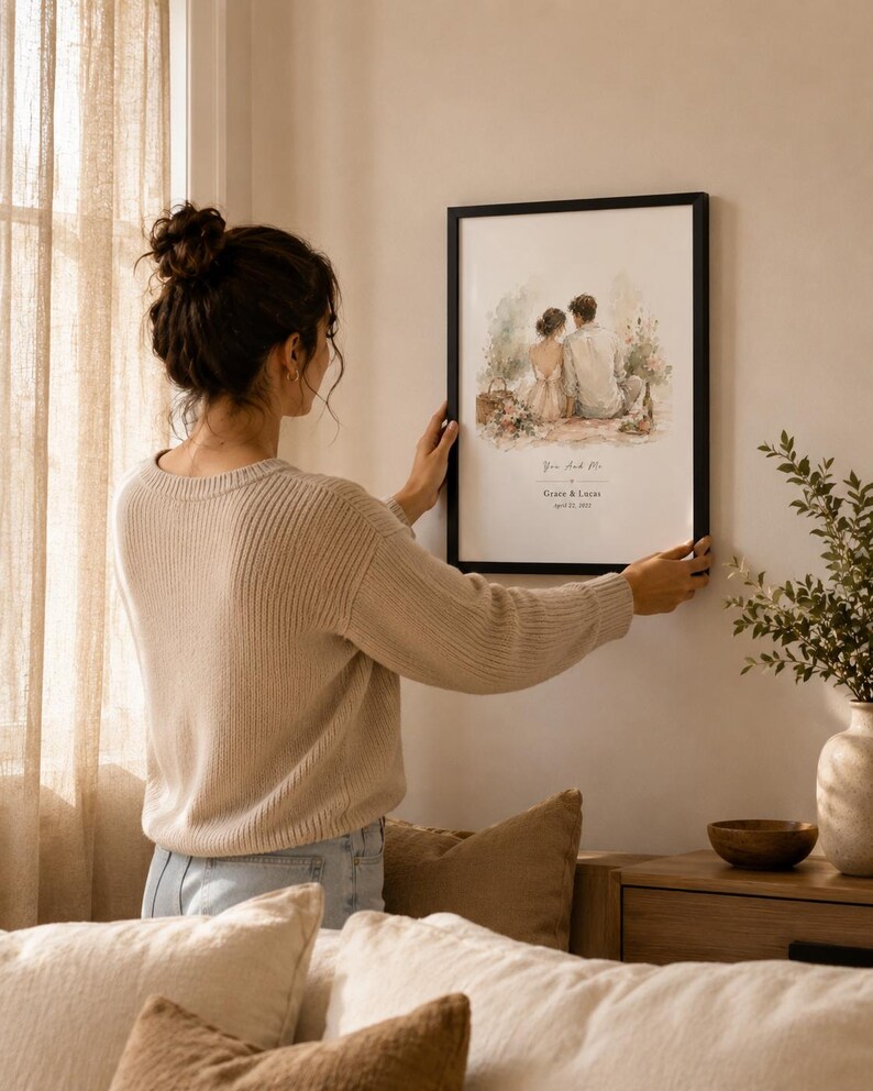K&ouml;nnte beinhalten: Ein gerahmter Aquarelldruck mit einem Paar, mit dem Text "You and Me" sowie Namen und Datum. Das schwarz gerahmte Kunstwerk wird an einer Wand aufgeh&auml;ngt. Das Bild hat eine neutrale Farbpalette und befindet sich in einer h&auml;uslichen Umgebung.