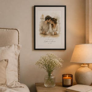 May include: A framed watercolor print depicts a couple sharing a tender moment, holding mugs. The print is in a black frame and hangs above a wooden nightstand. A vase of white flowers, a lit candle, and a lamp with a beige shade are also on the nightstand.