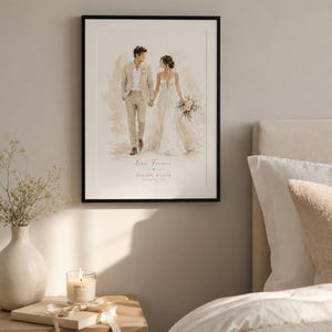 May include: A framed watercolor print of a couple holding hands, with the text "Our Forever" and names and a date. The artwork is in a black frame and is displayed on a wall. A nightstand with a candle and a vase of flowers is in the foreground.