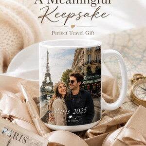 Peut inclure: Mug en c&eacute;ramique blanche avec une photo d'un couple &agrave; Paris, avec la Tour Eiffel en arri&egrave;re-plan. Le mug porte l'inscription "Paris 2025" et "Ella & Henry". Un souvenir sur le th&egrave;me du voyage.