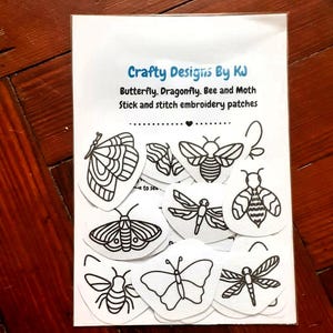 May include: A white rectangular card featuring the text Crafty Designs By KJ Butterfly, Dragonfly, Bee and Moth Stick and stitch embroidery patches. The card displays multiple black and white line art illustrations of insects including butterflies, dragonflies, bees, and moths.