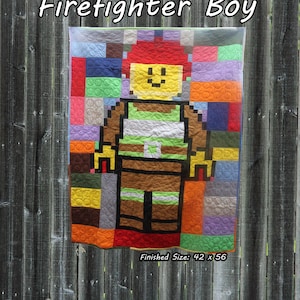 May include: A quilt featuring a pixelated firefighter character with a yellow head, red hair, and brown uniform, surrounded by a colorful block-patterned background. The text Firefighter Boy and Finished Size: 42 x 56 inches are visible on the image.