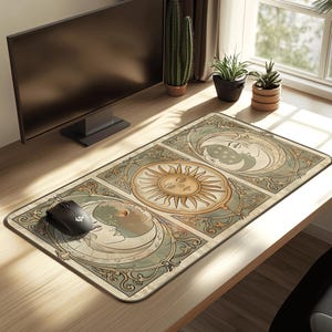 Puede incluir: Alfombrilla de ratón rectangular con un diseño celestial con un motivo de sol y luna en beige, verde azulado y dorado. La alfombrilla está sobre un escritorio de madera con un ratón de ordenador negro. Un monitor de ordenador y plantas están en el fondo.