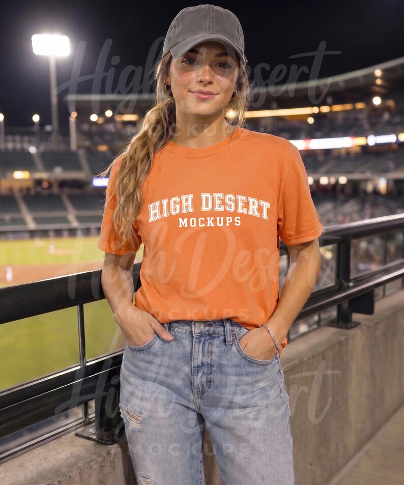 Peut inclure: Une casquette de baseball gris anthracite et un t-shirt orange &agrave; manches courtes avec le texte blanc HIGH DESERT MOCKUPS dans une police universitaire, associ&eacute;s &agrave; un jean bleu clair avec des d&eacute;tails us&eacute;s sur le devant des jambes.