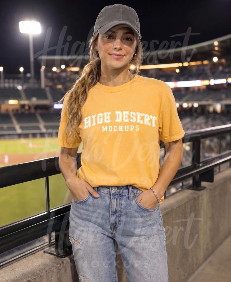 Peut inclure: Un t-shirt &agrave; manches courtes jaune moutarde avec le texte blanc HIGH DESERT MOCKUPS imprim&eacute; sur la poitrine. Le haut est associ&eacute; &agrave; une casquette de baseball gris anthracite et &agrave; un jean en denim bleu clair us&eacute; avec des d&eacute;chirures aux genoux.