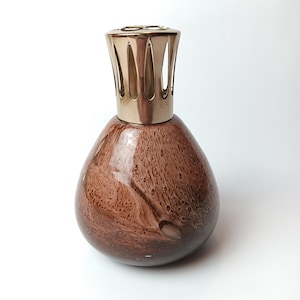 May include: A brown glass fragrance lamp with a gold-coloured metal top. The lamp has a teardrop shape with a speckled pattern in shades of brown. The metal top features vertical slits for fragrance diffusion.
