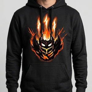 May include: Black hooded sweatshirt featuring a stylized graphic of a fiery creature with orange and yellow flames. The design includes a detailed face and body, set against a dark background. The hoodie has a drawstring hood and a front pocket.