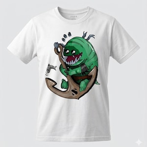 Puede incluir: Camiseta blanca con una ilustración de dibujos animados de una criatura verde con dientes afilados, posada sobre un ancla marrón. Un pequeño pez nada cerca. La camiseta tiene cuello redondo y es de material suave.