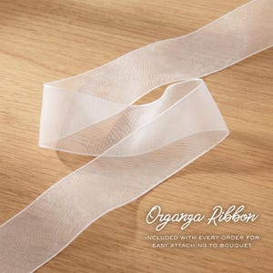 May include: A sheer white organza ribbon with a smooth texture and finished edges. The text Organza Ribbon INCLUDED WITH EVERY ORDER FOR EASY ATTACHING TO BOUQUET is printed in white script and sans-serif font on the lower right side of the image.