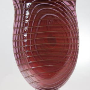 Handblown red-brown glass vase with lavender spirals and iridescent lip.