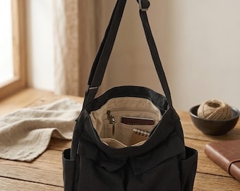 Bolso bandolera de lona negra: organizador cruzado con múltiples bolsillos y correa ajustable.