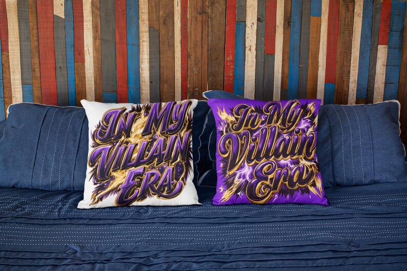May include: Two decorative cushions with the text "In My Villain Era" in purple and gold lettering. One cushion is white, the other is purple. The cushions are on a blue bed with blue cushions and a colourful wooden background.