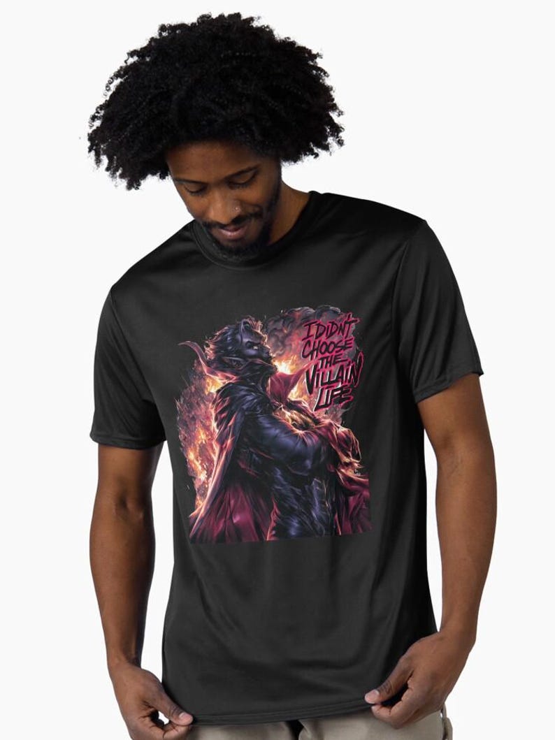 Peut inclure: T-shirt noir avec un graphisme de m&eacute;chant en cape sombre avec des accents rouges et des flammes. Le texte "I DIDN'T CHOOSE THE VILLAIN LIFE" est affich&eacute; dans une bulle rouge. Le t-shirt est port&eacute; par une personne.