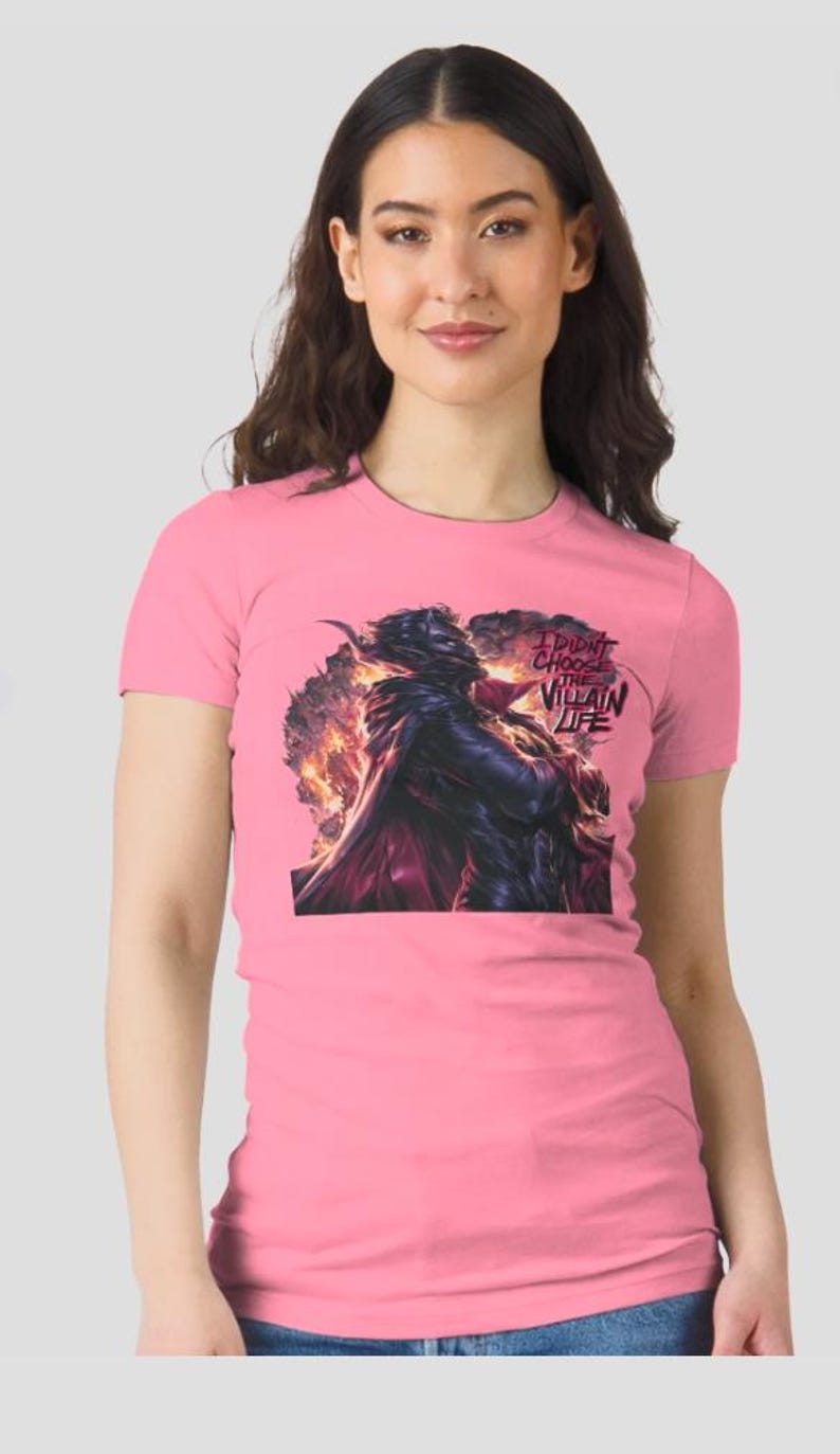Peut inclure: T-shirt rose avec un motif d'une figure sombre sur fond de flammes et le texte "I DIDN'T CHOOSE THE VILLAIN LIFE". Le t-shirt est en mati&egrave;re souple et &agrave; manches courtes.