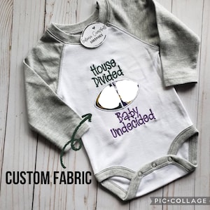 Body de bebé bordado con el diseño "Casa Dividida". Totalmente personalizable. Tú eliges los equipos, los colores, etc.