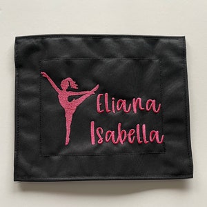 May include: Black fabric square with pink embroidery of a dancer silhouette and the names "Eliana Isabella".