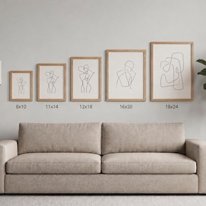 May include: A collection of five framed art prints featuring minimalist line drawings of figures. The prints are displayed above a beige sofa, with sizes ranging from 8x10 inches to 18x24 inches. The frames are light-colored wood.
