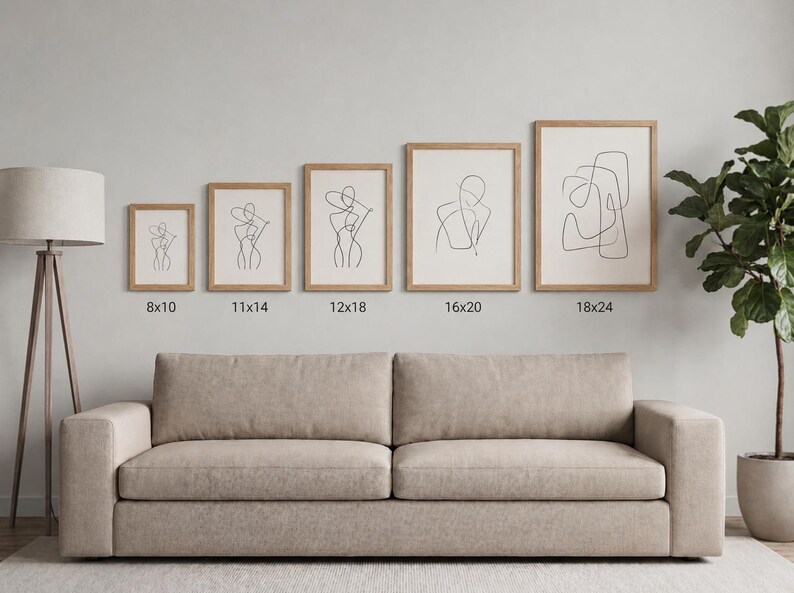 May include: A collection of five framed art prints featuring minimalist line drawings of figures. The prints are displayed above a beige sofa, with sizes ranging from 8x10 inches to 18x24 inches. The frames are light-colored wood.