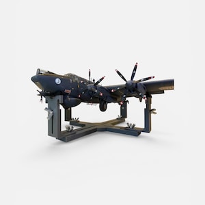 Könnte beinhalten: Ein dunkelblaues Modellflugzeug mit mehreren Motoren, das auf einem schwarzen, verstellbaren Ständer montiert ist. Das Modell verfügt über vier Propeller mit rot-weißen Spitzen, eine Cockpithaube und ein kreisförmiges weißes Emblem am Rumpf.