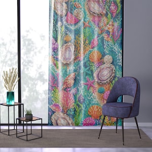 Puede incluir: Una cortina vibrante con un diseño marino, que presenta conchas marinas, estrellas de mar y corales en tonos rosa, naranja y verde sobre un fondo turquesa. Una silla azul con patas negras está frente a la cortina.