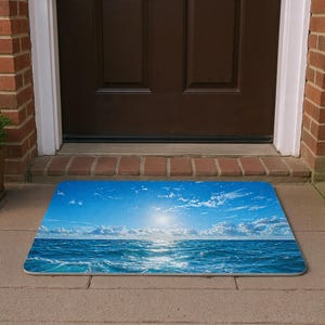 Könnte beinhalten: Eine rechteckige Fußmatte mit einer lebendigen Ozeanszene unter einem strahlend blauen Himmel mit weißen Wolken. Das Design zeigt die Reflexion der Sonne auf dem Wasser und schafft einen einladenden Eingang.