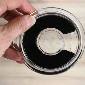 May include: Clear plastic lid with a black rubber seal and a silver handle. The lid has the words "BULA" and "12 oz" printed on it.