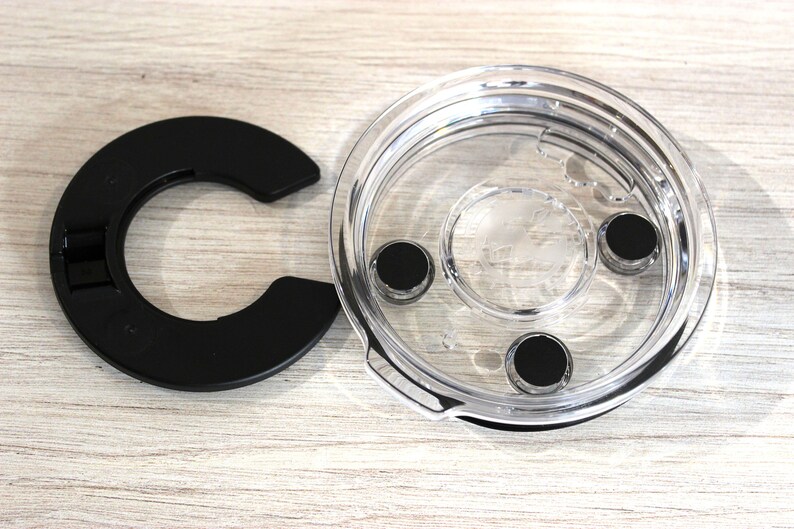 May include: A clear plastic lid with a black rubber ring and three black rubber feet. The lid is designed to fit on a container.