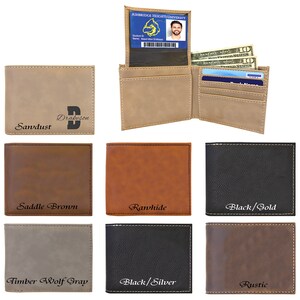 May include: A collection of bi-fold wallets in various colors including sand, saddle brown, rawhide, black, gray, and rustic brown. Each wallet features visible stitching and custom text engravings like Sandust, Rawhide, and Black/Gold. One wallet is open.