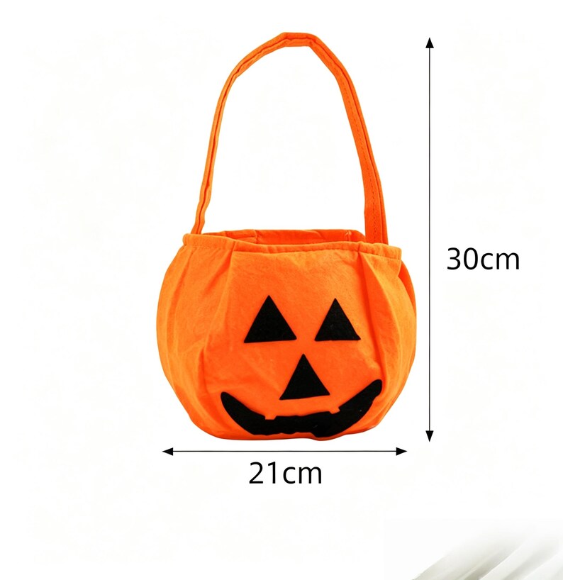 May include: An orange fabric pumpkin-shaped treat bag with a black felt jack-o'-lantern face featuring triangular eyes and a wide grin. The bag has a single handle and measures 30 cm in height and 21 cm in width as indicated by arrows.