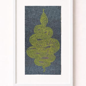 May include: Framed artwork with a green snake design on a blue-grey background. The snake is coiled and patterned. The artwork is in a white frame, ideal for wall decor. The artwork is in a white frame.