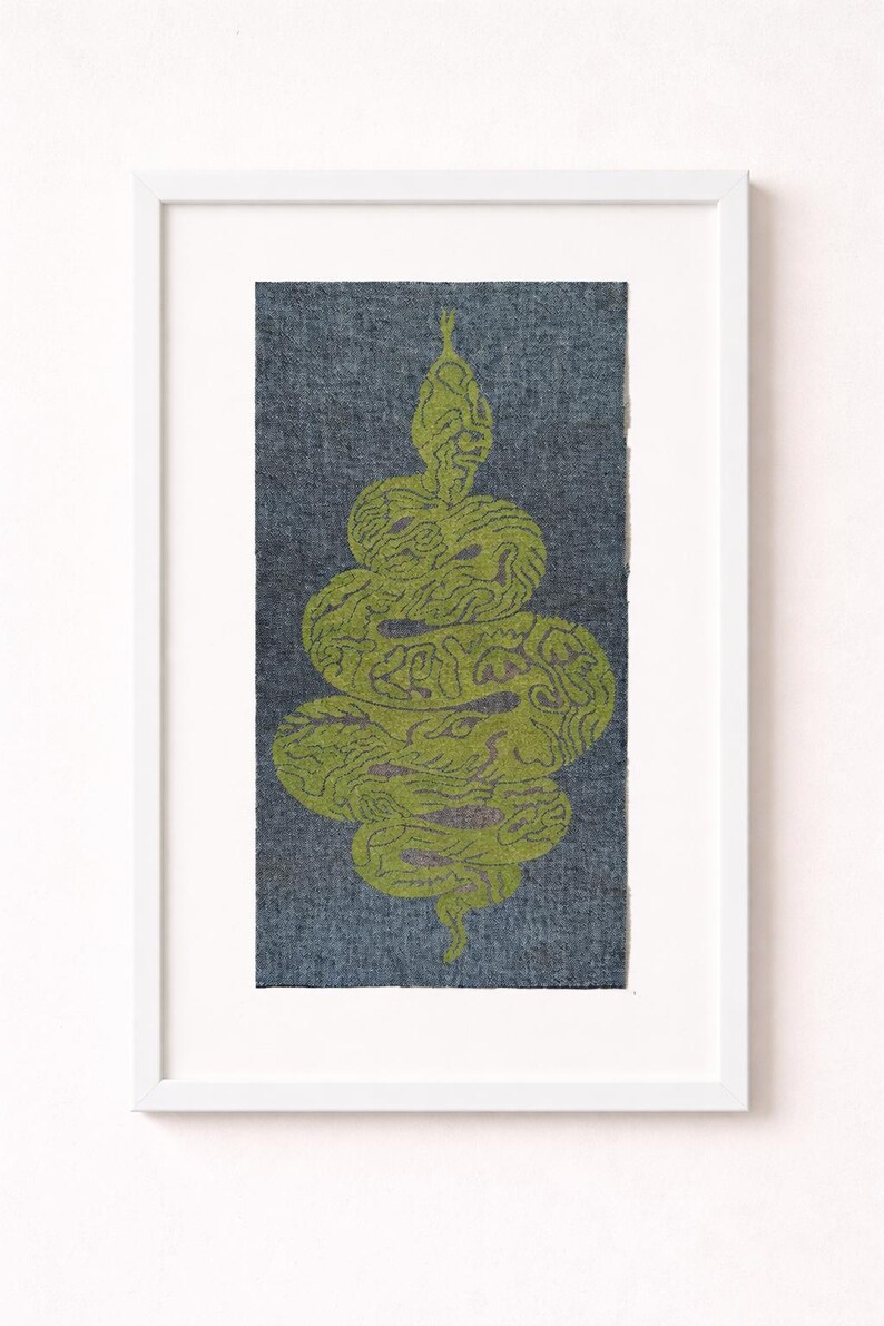 May include: Framed artwork with a green snake design on a blue-grey background. The snake is coiled and patterned. The artwork is in a white frame, ideal for wall decor. The artwork is in a white frame.