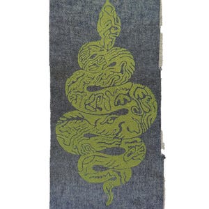 May include: A rectangular patch with a coiled snake design. The snake is a vibrant green against a textured grey background. The edges of the patch are frayed, giving it a raw, unfinished appearance.