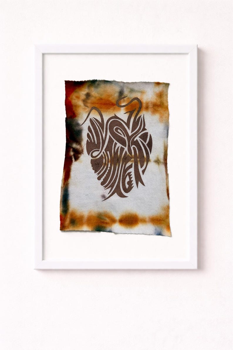 May include: Abstract artwork in a white frame. The art piece features a brown, stylized design on a tie-dye background with orange, brown, and blue hues. The artwork is a unique, decorative piece.