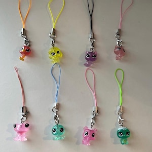 May include: Eight colorful plastic animal charms with matching lanyards. The charms include a variety of animals in orange, yellow, purple, pink, green, and blue. Each charm is attached to a silver-colored metal clasp.