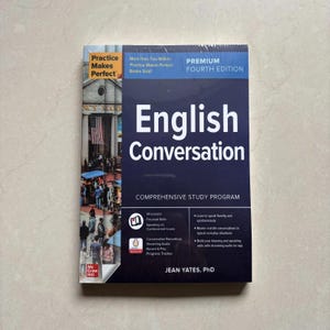 Puede incluir: Un libro de texto de conversación en inglés, cuarta edición, de Jean Yates, PhD. La cubierta azul oscuro presenta texto en blanco, una fotografía de una escena callejera con una bandera estadounidense y enumera funciones como 14 lecciones y audio.