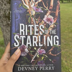 May include: A hardcover book titled "Rites of the Starling" by Devney Perry. The cover features a dark background with floral and vine illustrations, a sword, and the text "Discover the monster within."