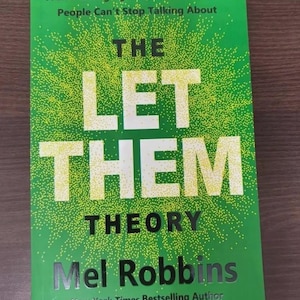 May include: A hardcover book titled "THE LET THEM THEORY" by Mel Robbins. The cover is green with white text and a pattern of small yellow dots. The book is a New York Times Bestseller.
