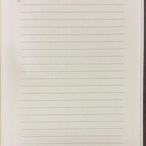 May include: Open notebook with lined pages. The word "NOTES" is printed at the top in a serif font. Decorative flourishes are present at the top left and bottom right corners of the page. The paper is off-white.