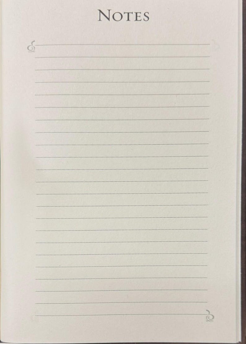 May include: Open notebook with lined pages. The word "NOTES" is printed at the top in a serif font. Decorative flourishes are present at the top left and bottom right corners of the page. The paper is off-white.