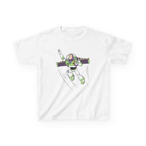 Puede incluir: Camiseta blanca con una ilustraci&oacute;n de dibujos animados de Buzz Lightyear en vuelo. El personaje se muestra con su traje de guardi&aacute;n espacial, con detalles verdes, morados y blancos. L&iacute;neas negras sugieren movimiento.