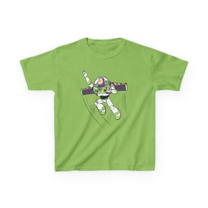 Puede incluir: Una camiseta verde lima con una ilustraci&oacute;n de dibujos animados de Buzz Lightyear volando. El personaje lleva un traje espacial blanco y verde con una mochila propulsora morada. El dise&ntilde;o es una representaci&oacute;n vibrante y juguetona del personaje animado.