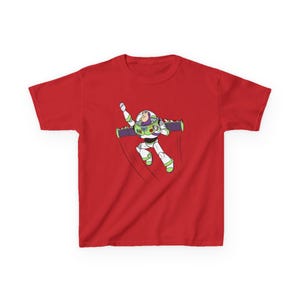 Puede incluir: Camiseta roja con una ilustraci&oacute;n de dibujos animados de Buzz Lightyear en pleno vuelo. El personaje lleva su ic&oacute;nico traje espacial blanco, verde y morado, con un brazo levantado. La camiseta est&aacute; hecha de un material suave.