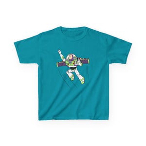 Puede incluir: Camiseta de color turquesa con un gr&aacute;fico de Buzz Lightyear en pose de vuelo. El personaje de dibujos animados lleva un traje espacial blanco y verde con una mochila propulsora morada. L&iacute;neas negras curvas indican movimiento.