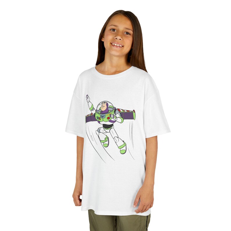 Puede incluir: Camiseta blanca con un gr&aacute;fico de Buzz Lightyear en vuelo. El personaje de dibujos animados se muestra en verde, blanco, morado y rojo. La camiseta es de cuello redondo.